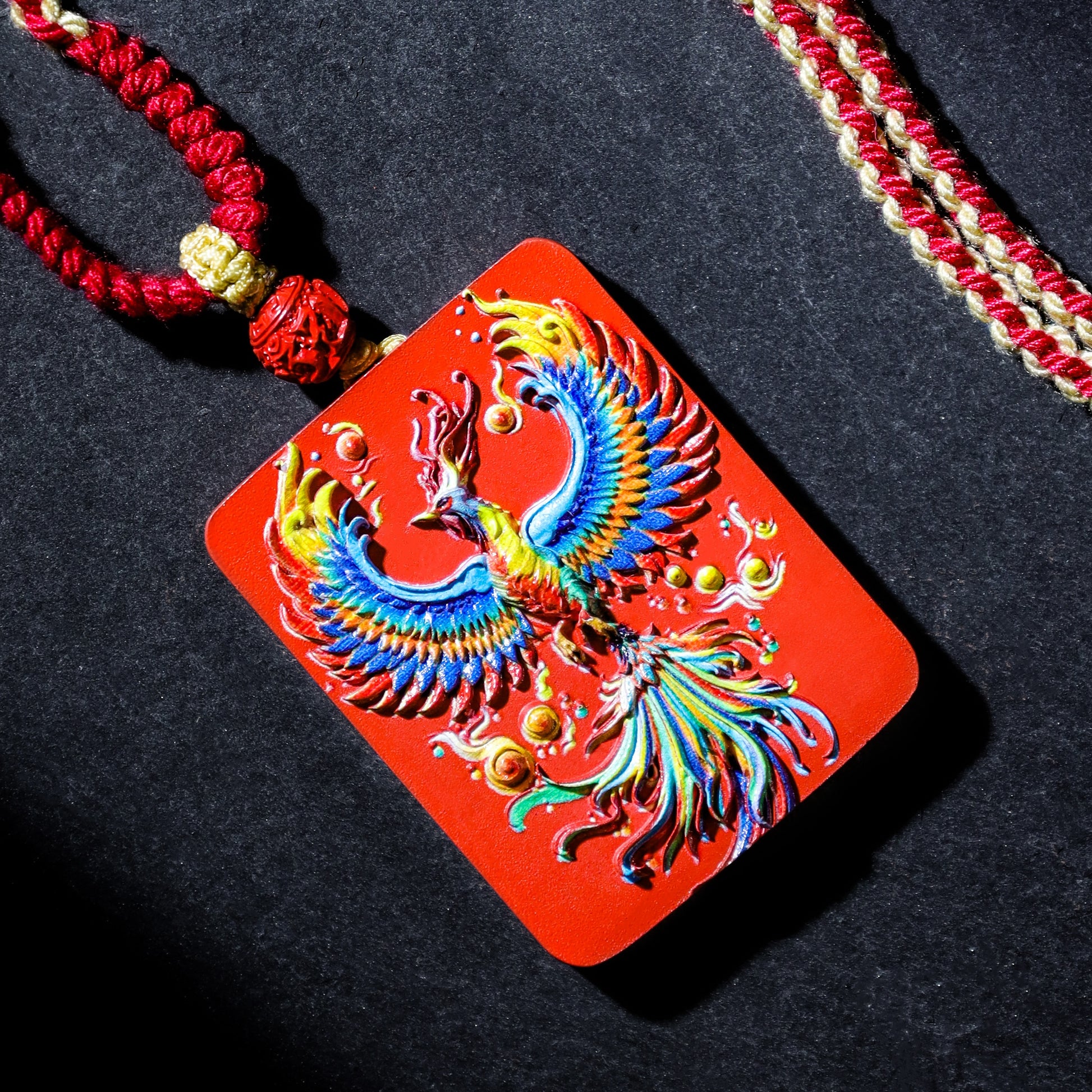 Cinnabar Fire Phoenix Thangka Pendant with colorful phoenix design and red cord, symbolizing rebirth and good luck.